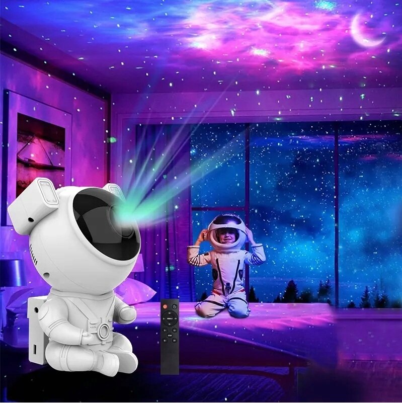 Na obrazie widać projektor w kształcie astronauty, który wyświetla gwiazdy i kolorowe światła na suficie pokoju. Obok projektora znajduje się pilot zdalnego sterowania, a w tle dziecko w stroju astronauty siedzi na łóżku.
