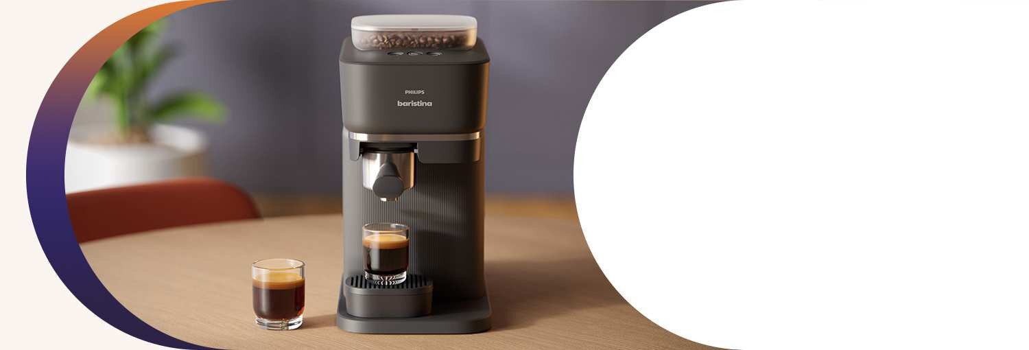 Na drewnianym stole stoi czarny ekspres do kawy z filiżanką espresso. Na ekspresie widoczny jest napis \'PHILIPS baristina\'.
