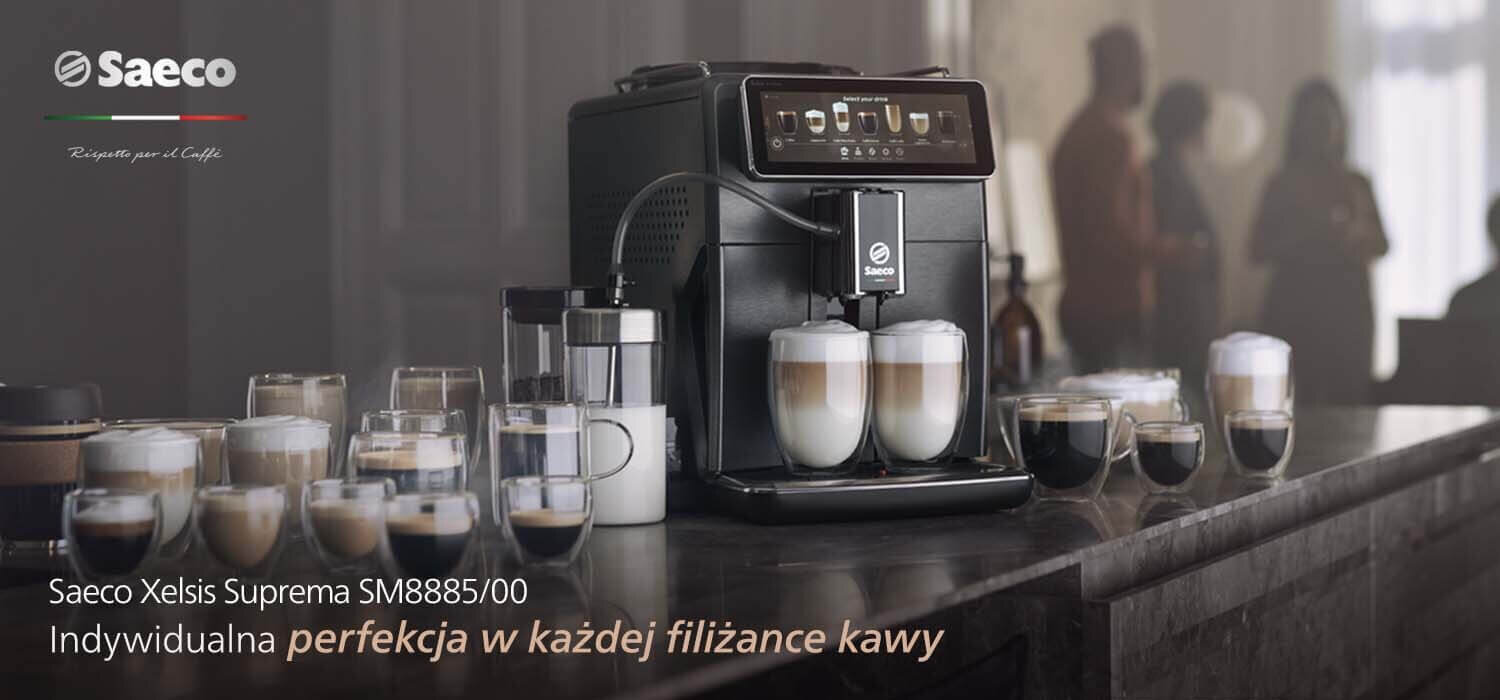 Na blacie stoi ekspres do kawy z logo Saeco, obok którego znajduje się kilka filiżanek z kawą. Widoczny jest tekst: \'Saeco Xelsis Suprema SM8885/00 Indywidualna perfekcja w każdej filiżance kawy\'.