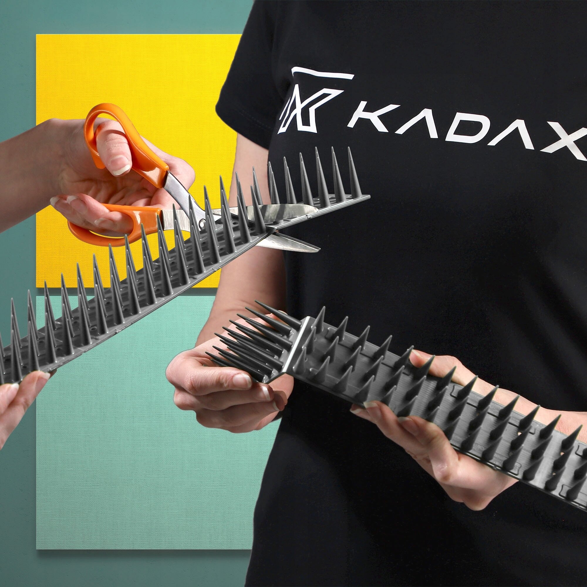 Osoba w czarnej koszulce z logo \'KADAX\' trzyma plastikowe kolce, które są przecinane nożyczkami. W tle widoczne są kolorowe prostokąty.