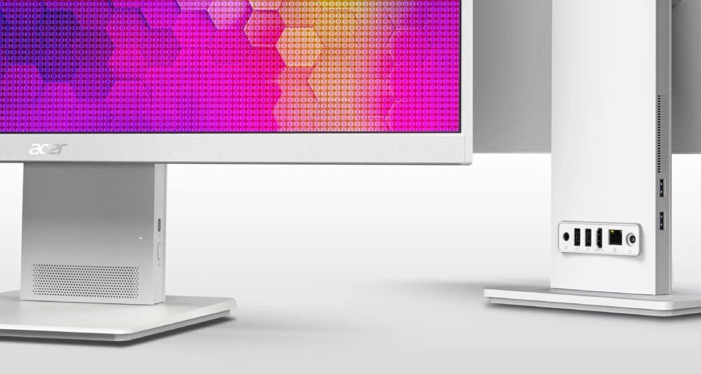 Obraz przedstawia komputer All in One z widocznym ekranem o kolorowym tle i podstawą w kolorze srebrnym. Na obudowie znajduje się logo \'acer\' oraz porty USB i inne złącza.