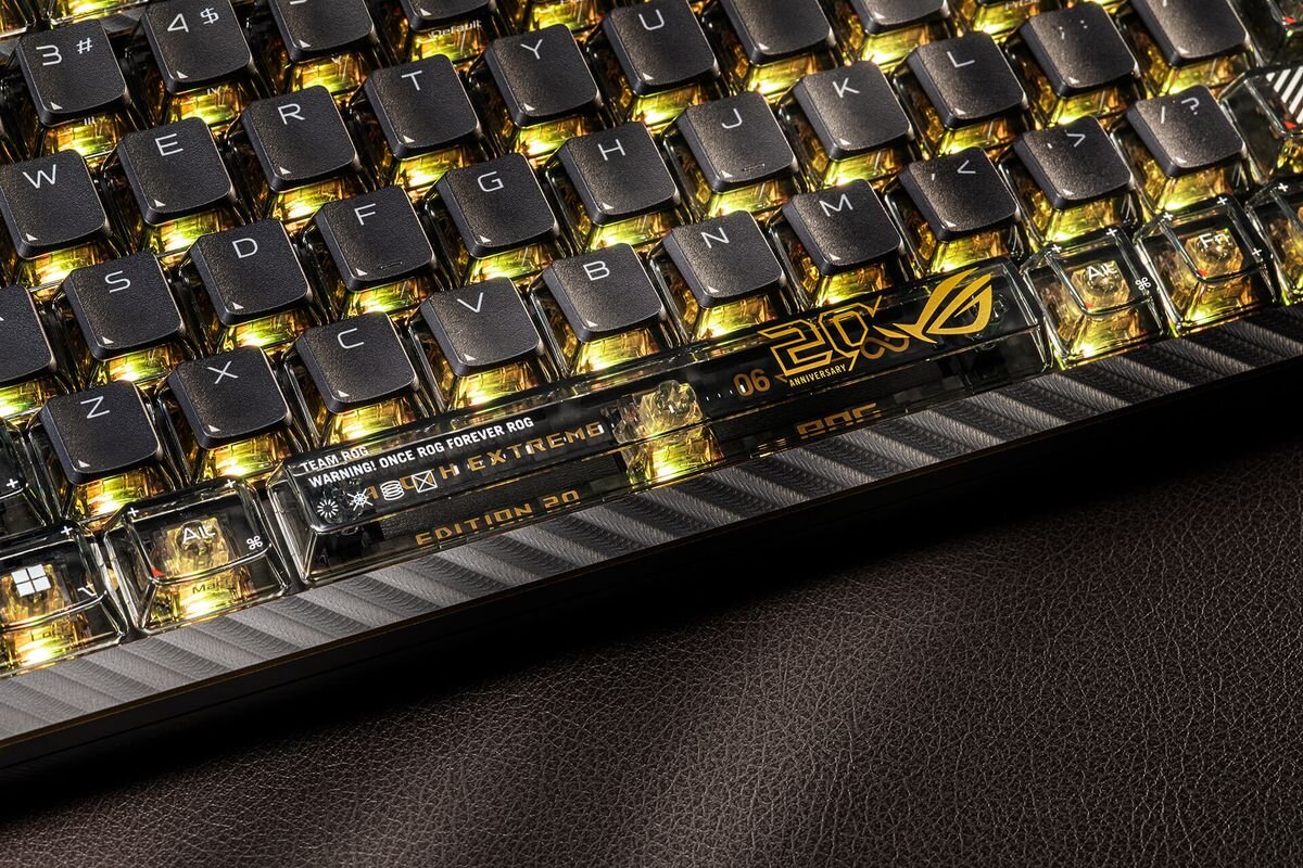 Klawiatura mechaniczna z podświetlanymi klawiszami, na której widoczne są napisy: \'TEAM ROG, ONCE ROG FOREVER ROG\', \'WARNING!\', \'EXTREME\', \'EDITION 20\' oraz logo \'20th ANNIVERSARY\'.