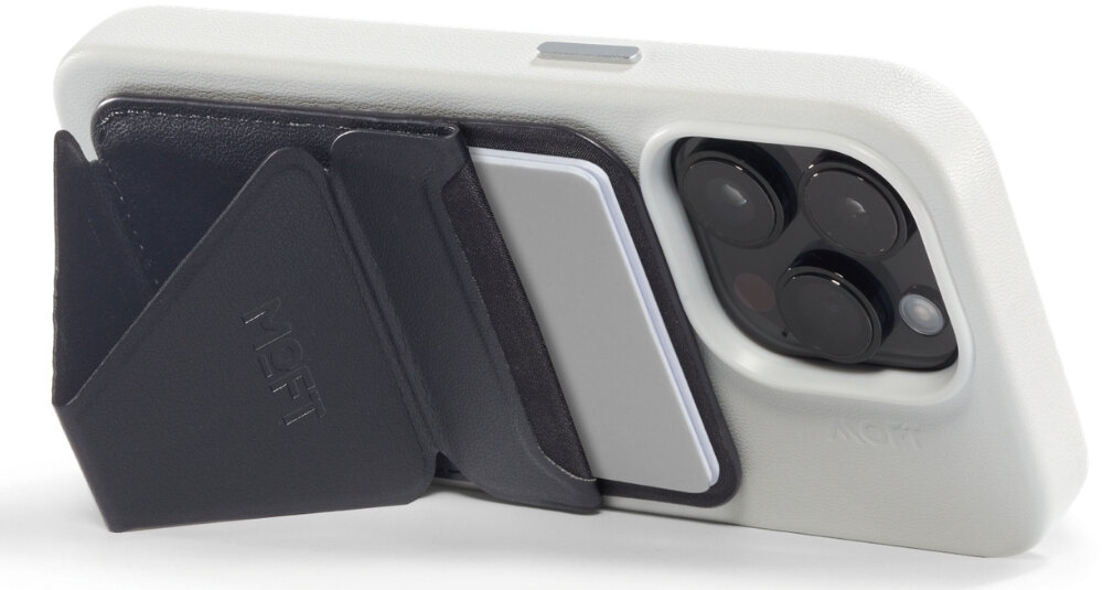 Czarny portfel MOFT Movas Snap-On MagSafe przymocowany do białego etui na telefon, z widocznymi trzema obiektywami aparatu. Na portfelu znajduje się wytłoczony napis \'MOFT\'.