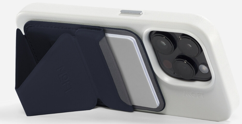 Na zdjęciu widać granatowy portfel MOFT Movas Snap-On MagSafe przymocowany do białego etui na telefon. Portfel jest otwarty, a w środku znajduje się karta.