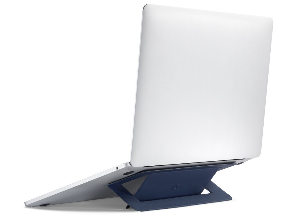 Na zdjęciu widać laptopa umieszczonego na granatowej podstawce, która unosi jego tył. Podstawka ma prosty, geometryczny kształt.