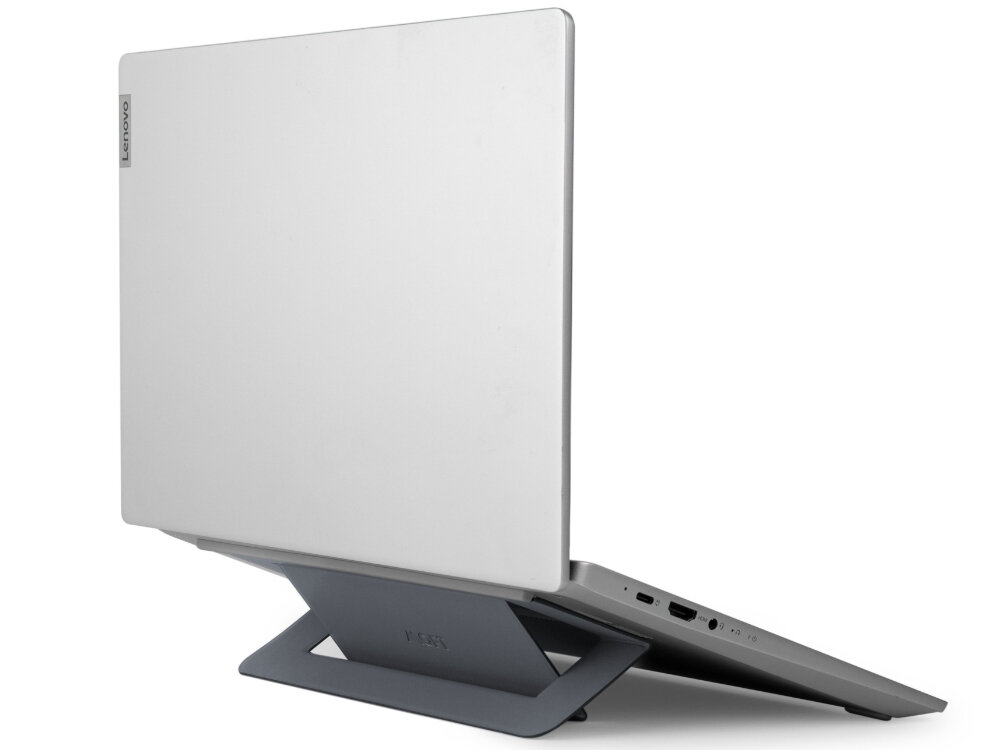 Na obrazie widoczny jest srebrny laptop ustawiony na szarej podstawce. Na laptopie znajduje się logo \'Lenovo\'.