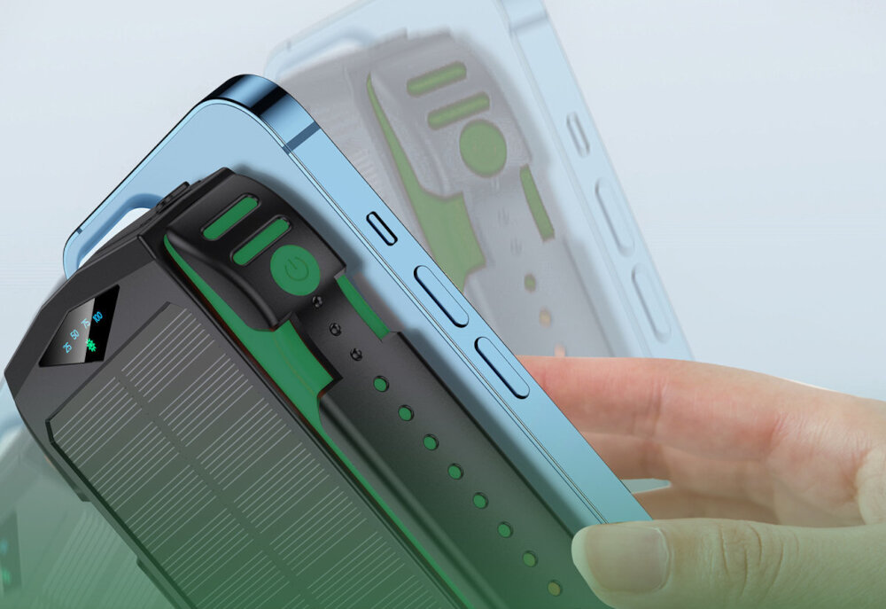 Na zdjęciu widać rękę trzymającą niebieski smartfon oraz czarno-zielony powerbank z widocznym przyciskiem zasilania i wskaźnikiem LED. Powerbank ma teksturowaną powierzchnię i zielone akcenty.