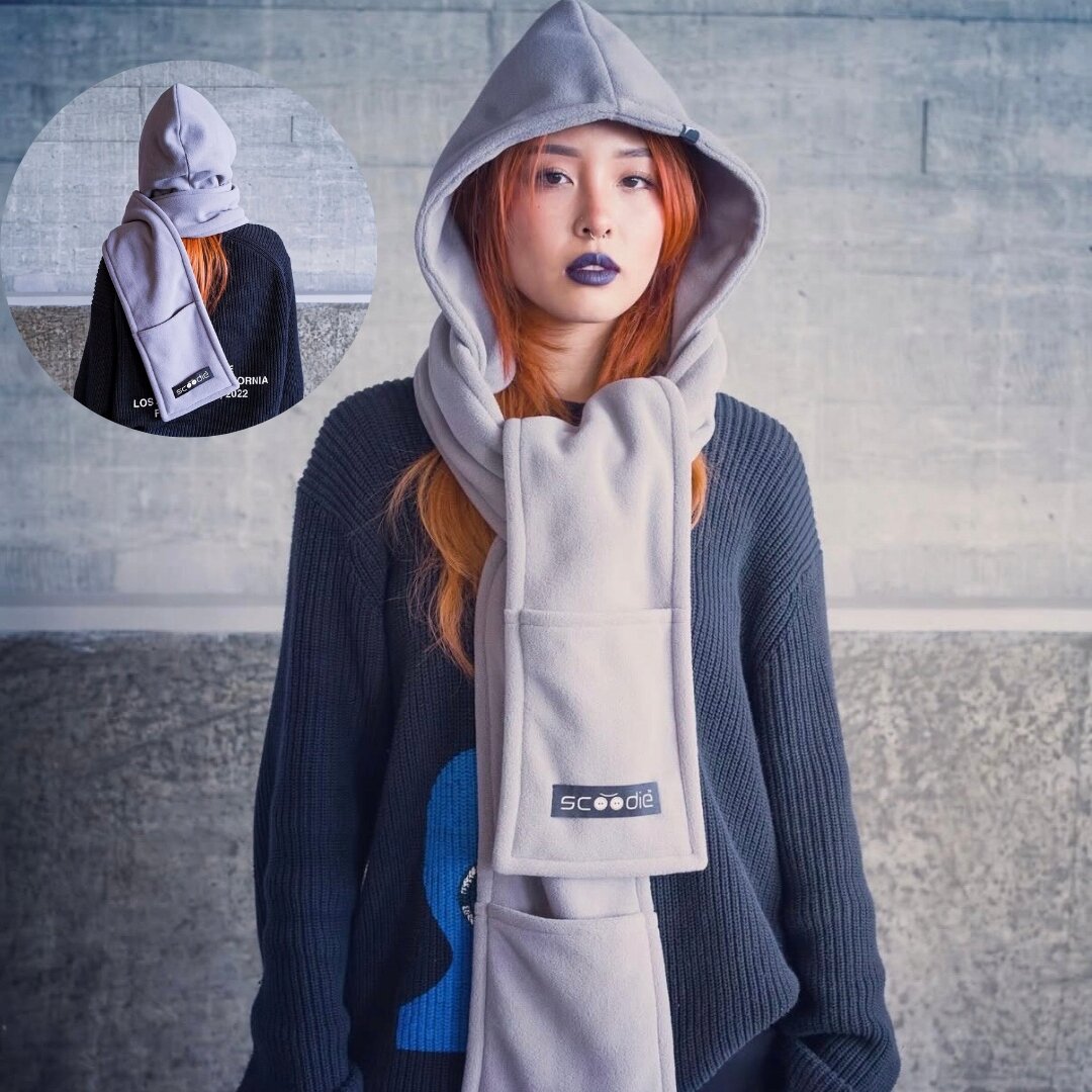 Osoba nosi szary kaptur z odpinanym szalikiem, na którym widnieje logo \'Scoodie\'. W tle znajduje się szara ściana, a w okrągłym wstawce pokazano tył produktu.