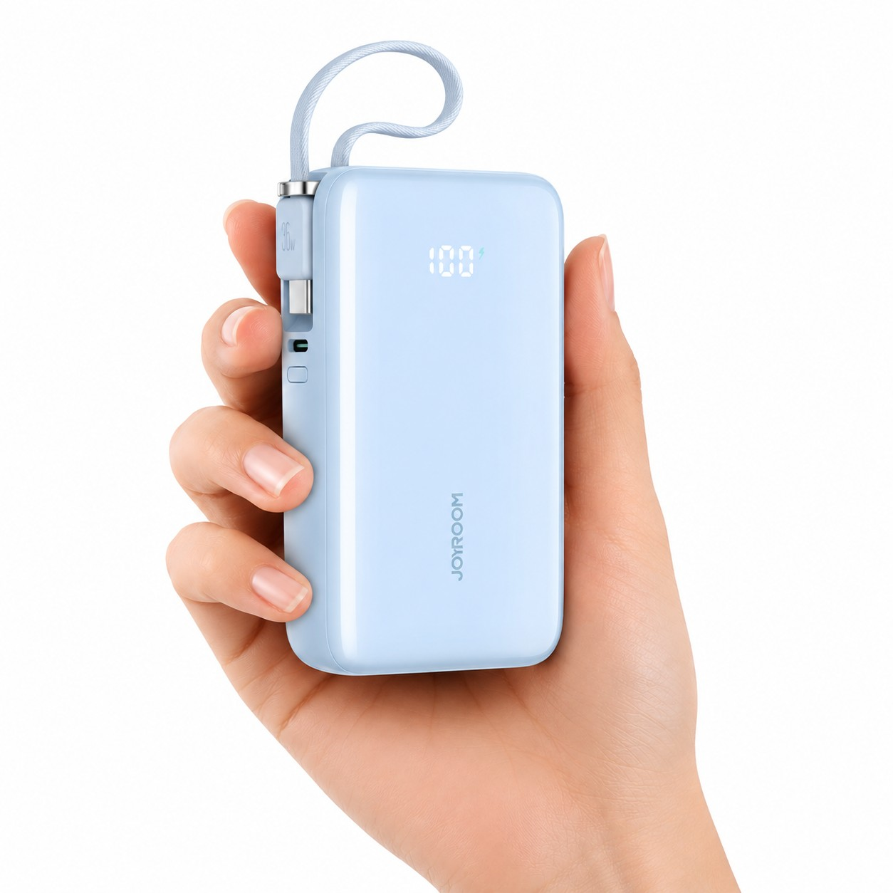 Osoba trzyma niebieski powerbank z wyświetlaczem pokazującym \'100%\'. Na urządzeniu widoczne jest logo \'JORROOM\' oraz wbudowany kabel USB-C.