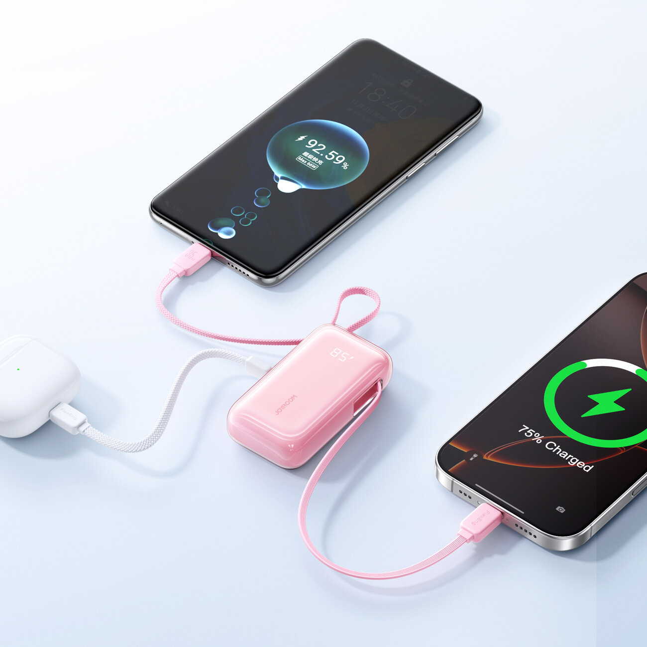Na obrazie widać różowy powerbank z wyświetlaczem \'85%\' podłączony do dwóch urządzeń mobilnych. Jeden z telefonów pokazuje stan naładowania \'92.59%\', a drugi \'75% Charged\'.