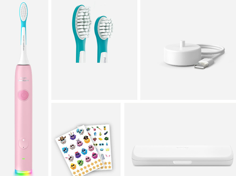 Na obrazie widoczna jest różowa szczoteczka soniczna z wymiennymi końcówkami, ładowarka USB, zestaw naklejek oraz etui. Szczoteczka ma napis \'PHILIPS Sonicare\'.