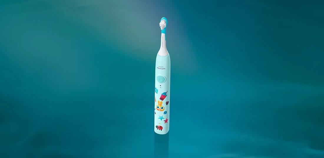 Szczoteczka soniczna w kolorze turkusowym z kolorowymi grafikami na uchwycie, widoczna na jednolitym tle. Na uchwycie znajduje się logo \'Philips Sonicare\'.