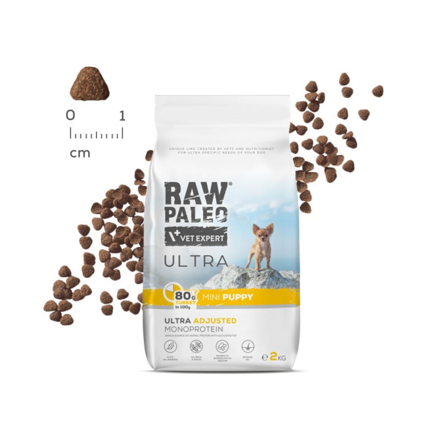 Opakowanie suchej karmy dla szczeniąt z napisem \'RAW PALEO VET EXPERT ULTRA MINI PUPPY\'. Obok opakowania widoczne są granulki karmy oraz miarka w centymetrach.