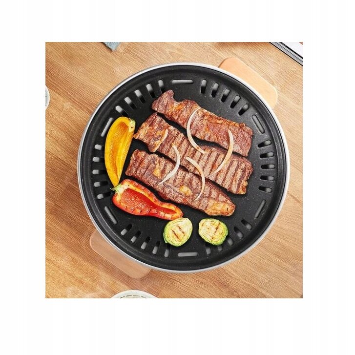 Na okrągłym grillu znajdują się kawałki mięsa, plasterki cebuli, papryka i cukinia. Grill umieszczony jest na drewnianym blacie.