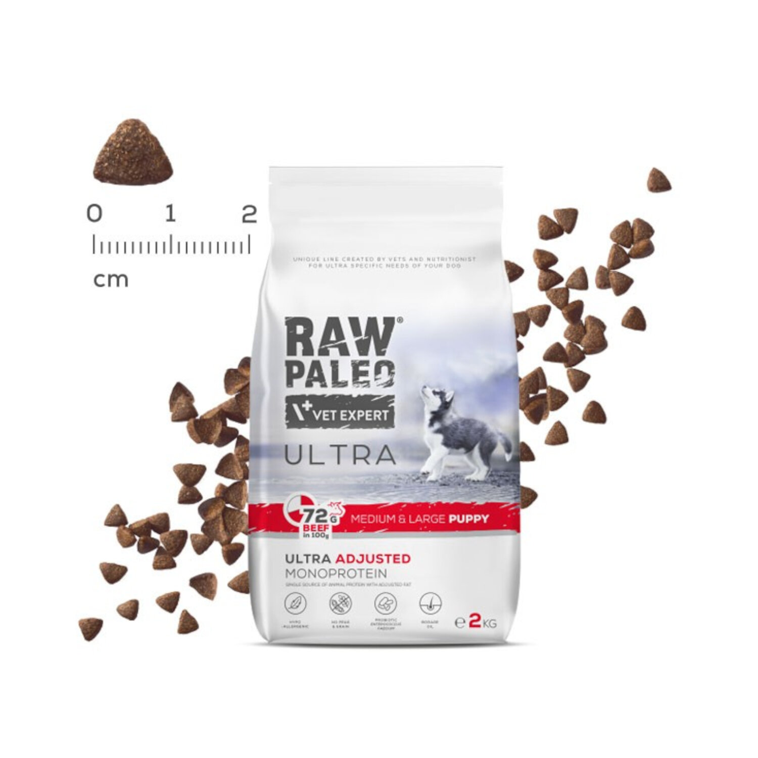 Opakowanie suchej karmy dla szczeniąt z napisem \'RAW PALEO VET EXPERT ULTRA\' oraz \'MEDIUM & LARGE PUPPY\'. Obok opakowania widoczne są granulki karmy i miarka w centymetrach.