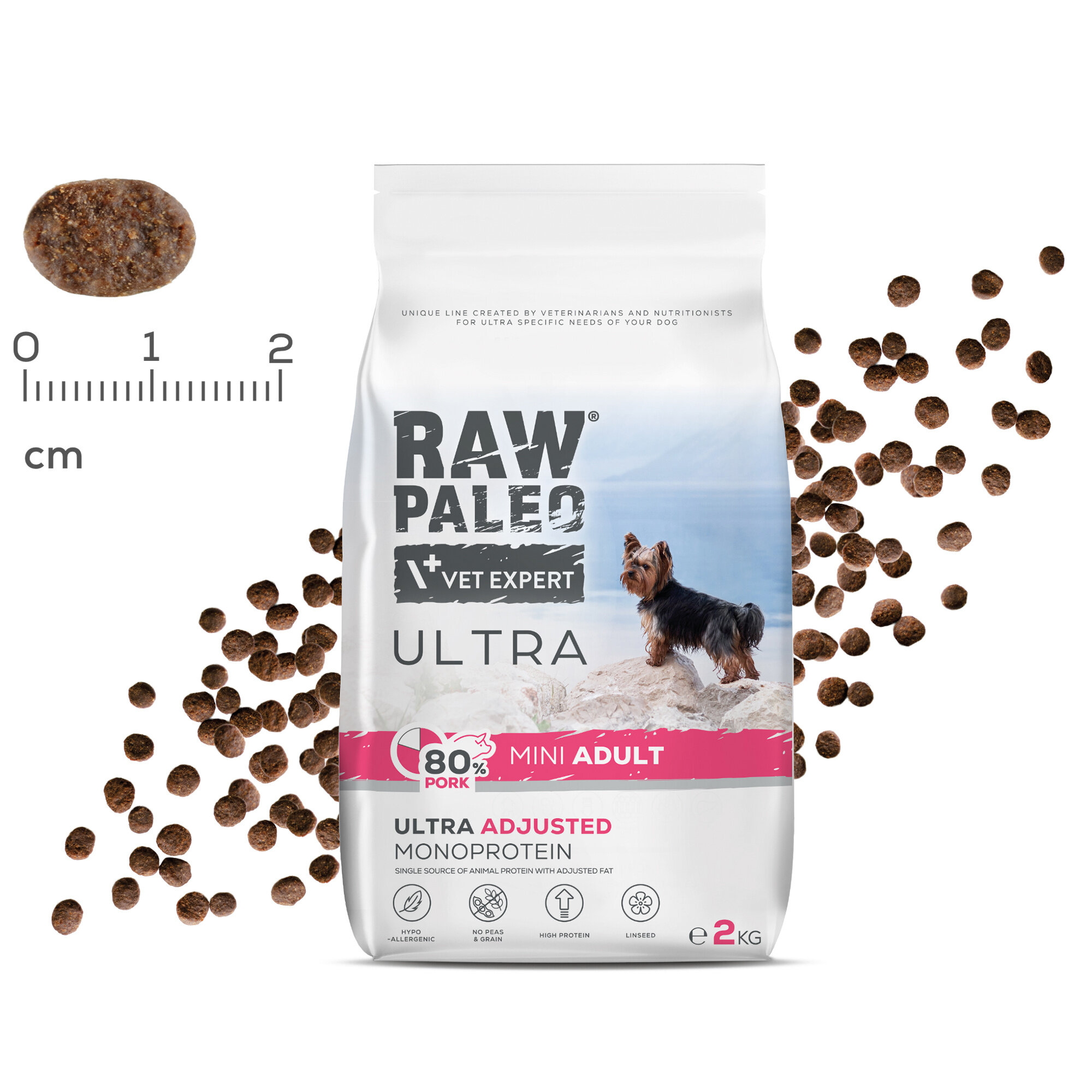 Opakowanie karmy dla psów z napisem \'RAW PALEO VET EXPERT ULTRA 80% PORK MINI ADULT ULTRA ADJUSTED MONOPROTEIN\'. Obok opakowania widoczne są granulki karmy oraz miarka w centymetrach.