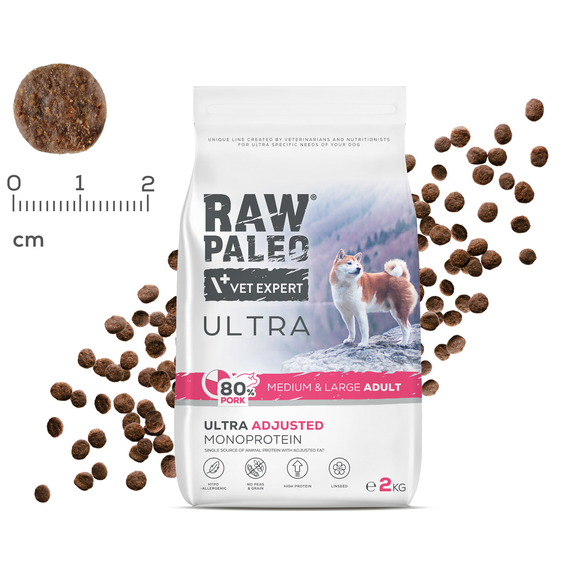 Opakowanie suchej karmy dla psów z napisem \'RAW PALEO VET EXPERT ULTRA 80% PORK MEDIUM & LARGE ADULT\'. Obok opakowania widoczne są granulki karmy oraz miarka w centymetrach.