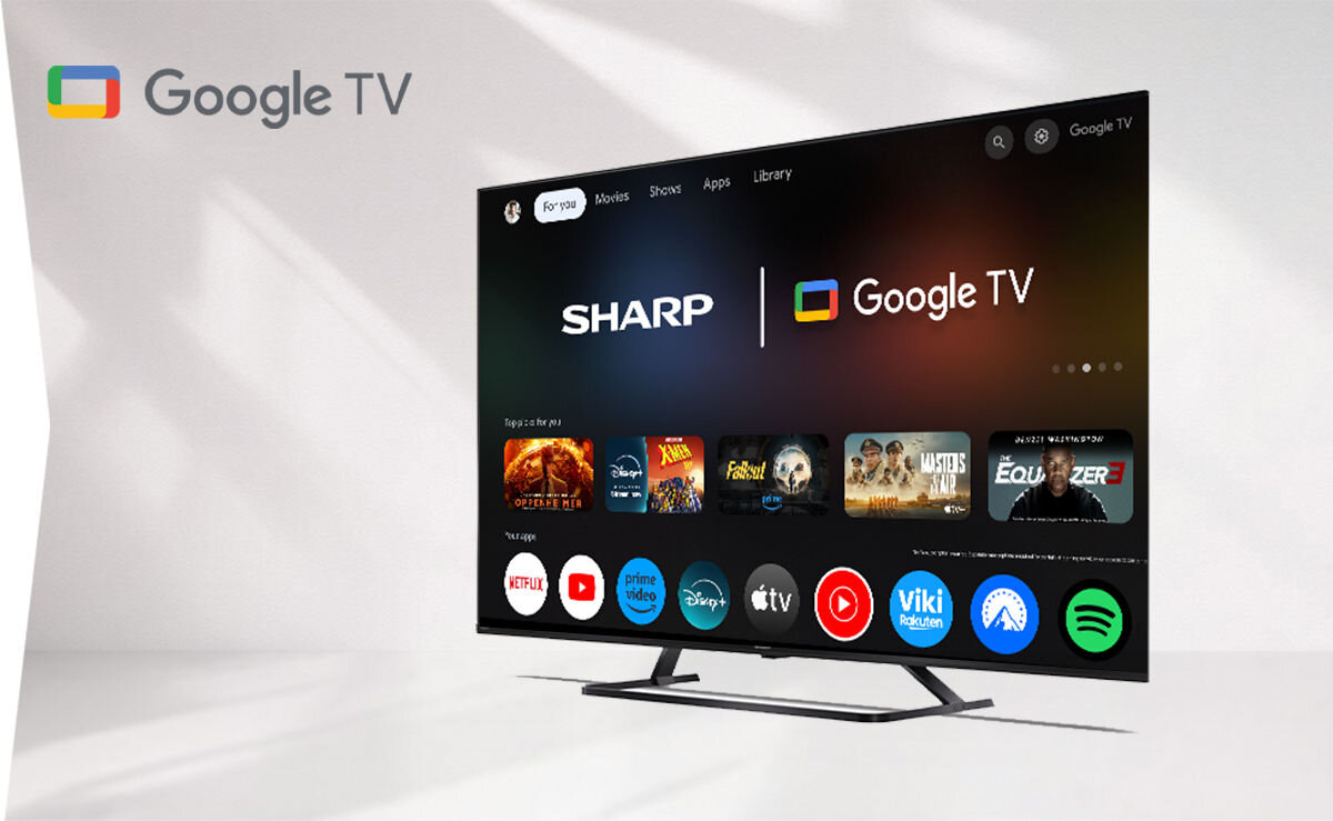 Telewizor z logo SHARP i Google TV na ekranie, wyświetlający interfejs z aplikacjami takimi jak Netflix, Prime Video, Disney+ i Spotify. Obok telewizora widoczne jest logo Google TV.