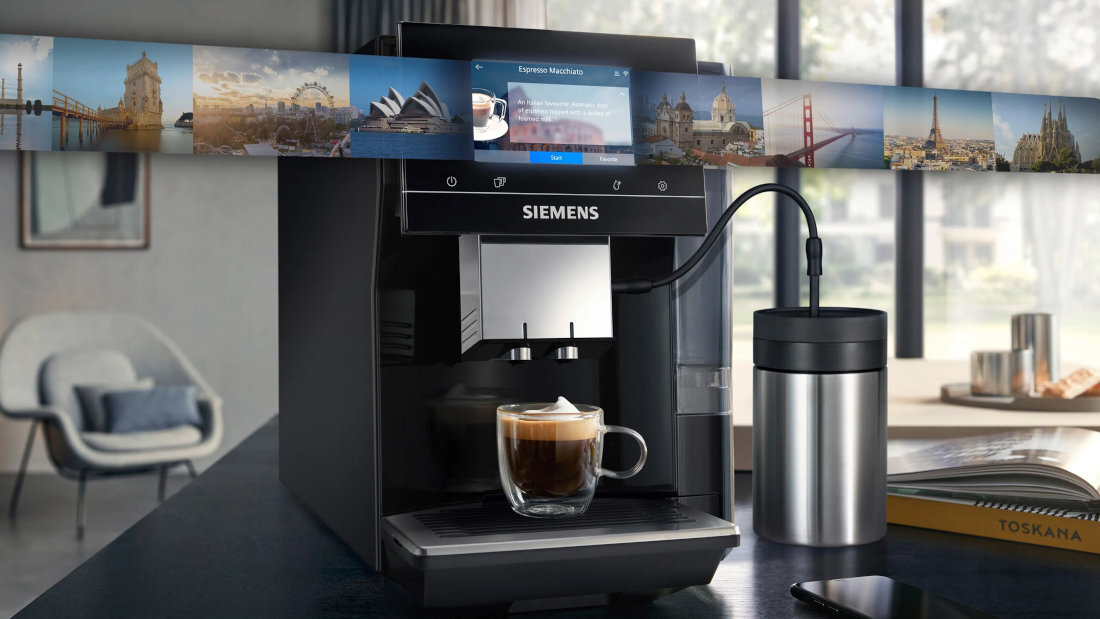 Czarny ekspres do kawy marki SIEMENS z wyświetlaczem, na którym widoczny jest napis \'Espresso Macchiato\'. Obok ekspresu stoi metalowy pojemnik, a na blacie znajduje się filiżanka z kawą.