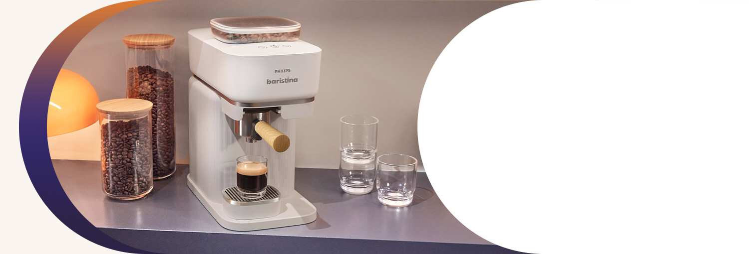 Na blacie stoi ekspres do kawy z filiżanką espresso, obok znajdują się dwa słoje z ziarnami kawy i dwie szklanki. Na ekspresie widnieje napis \'PHILIPS baristina\'.