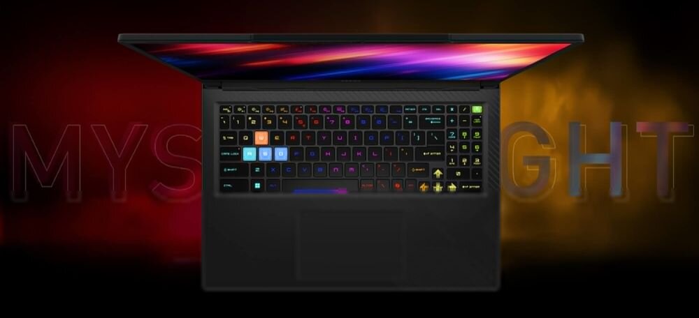 Obraz przedstawia otwarty laptop z podświetlaną klawiaturą w różnych kolorach. W tle widoczny jest napis \'MYSTERY LIGHT\'.