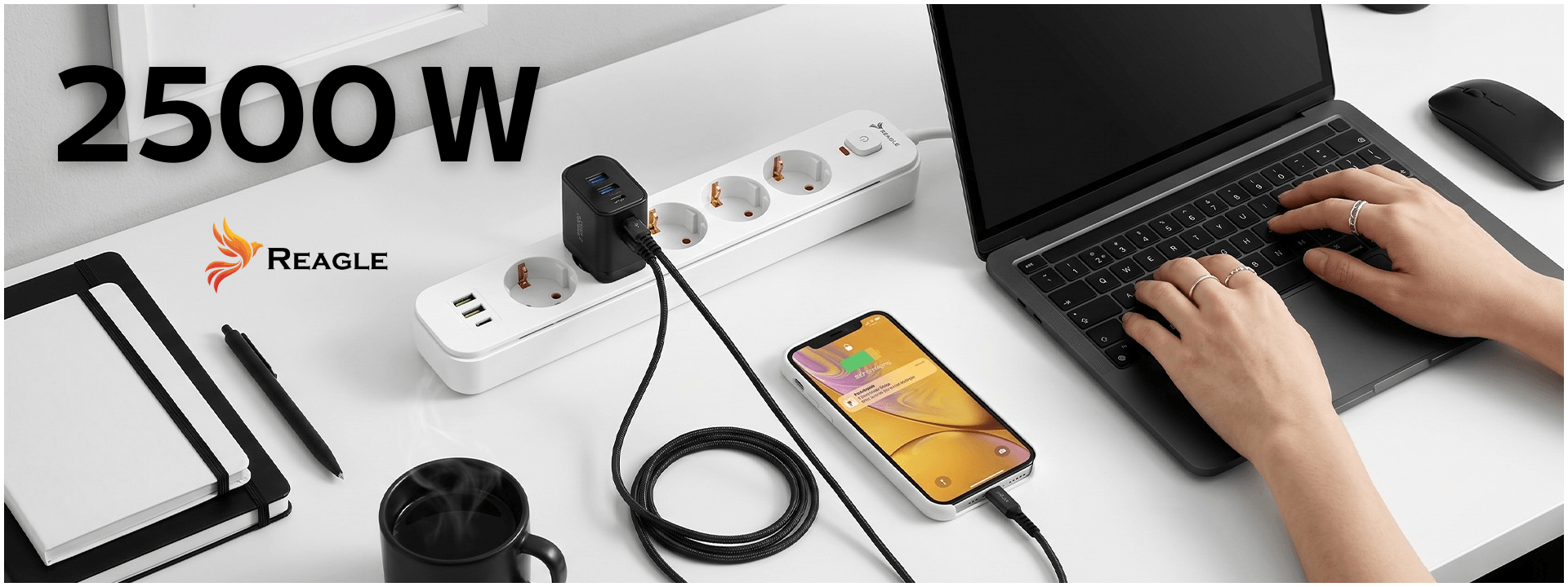 Na biurku znajduje się listwa zasilająca z pięcioma gniazdami, dwoma portami USB-A i jednym USB-C, obok laptopa i smartfona. Widoczny jest napis \'2500 W\' oraz logo \'Reagle\'.