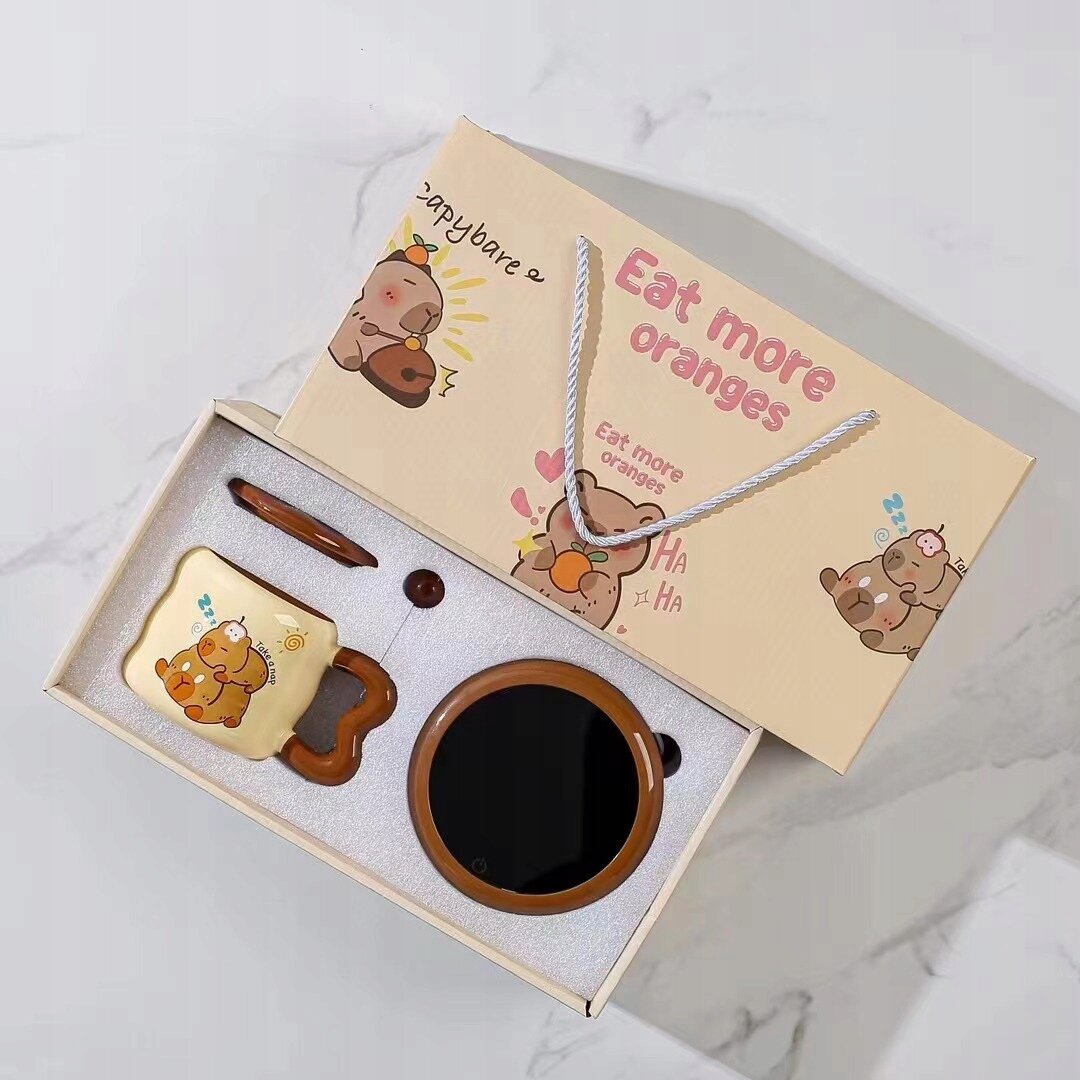 Zestaw prezentowy zawiera podgrzewacz do kubka i kubek ceramiczny z motywem misia. Na opakowaniu widnieje napis \'Eat more oranges\' oraz ilustracje misiów.