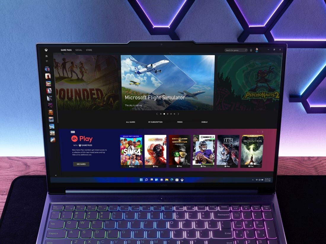 Laptop z wyświetlonym ekranem, na którym widoczny jest interfejs aplikacji z grami, w tym \'Microsoft Flight Simulator\'. Klawiatura laptopa jest podświetlona różnokolorowym światłem.