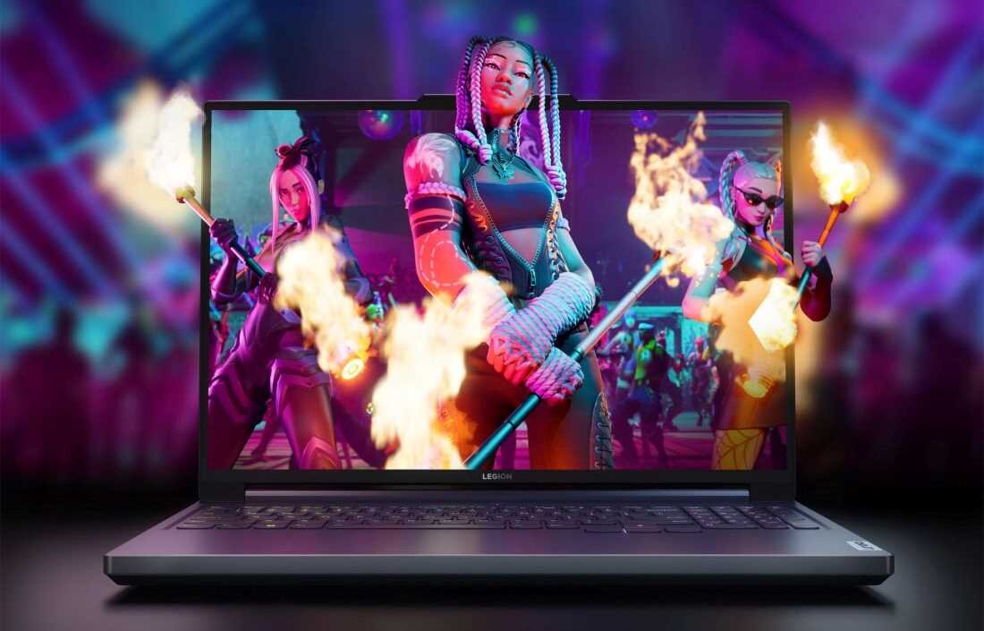 Laptop z wyświetlaczem pokazującym dynamiczną scenę z trzema postaciami trzymającymi płonące pochodnie. Na obudowie widoczne jest logo \'Legion\'.