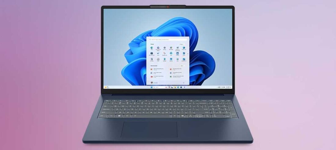 Laptop z otwartym ekranem wyświetlającym interfejs systemu Windows 11, na tle gradientu w odcieniach różu i fioletu. Klawiatura jest podświetlona, a obudowa ma ciemny kolor.