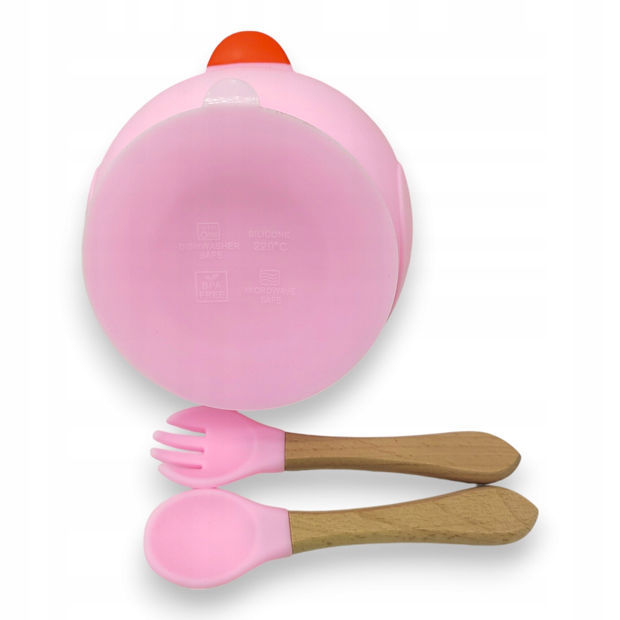 Różowa miseczka z przyssawką, widoczna od spodu z napisami: \'DISHWASHER SAFE\', \'BPA FREE\', \'SILICONE 220°C\', \'MICROWAVE SAFE\'. Obok znajdują się różowa łyżka i widelec z drewnianymi uchwytami.