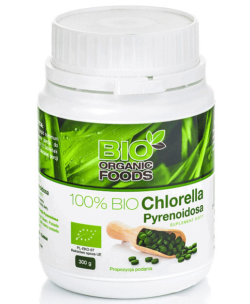 Biały pojemnik z etykietą przedstawiającą zielone liście i napisem \'BIO ORGANIC FOODS 100% BIO Chlorella Pyrenoidosa Suplement diety\'. Na etykiecie widoczny jest również symbol ekologiczny oraz informacja \'300 g\'.