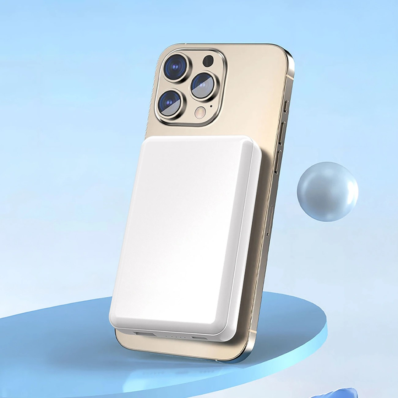 Na obrazie widoczny jest biały powerbank przymocowany magnetycznie do tylnej części smartfona. Tło jest niebieskie z unoszącą się kulą.