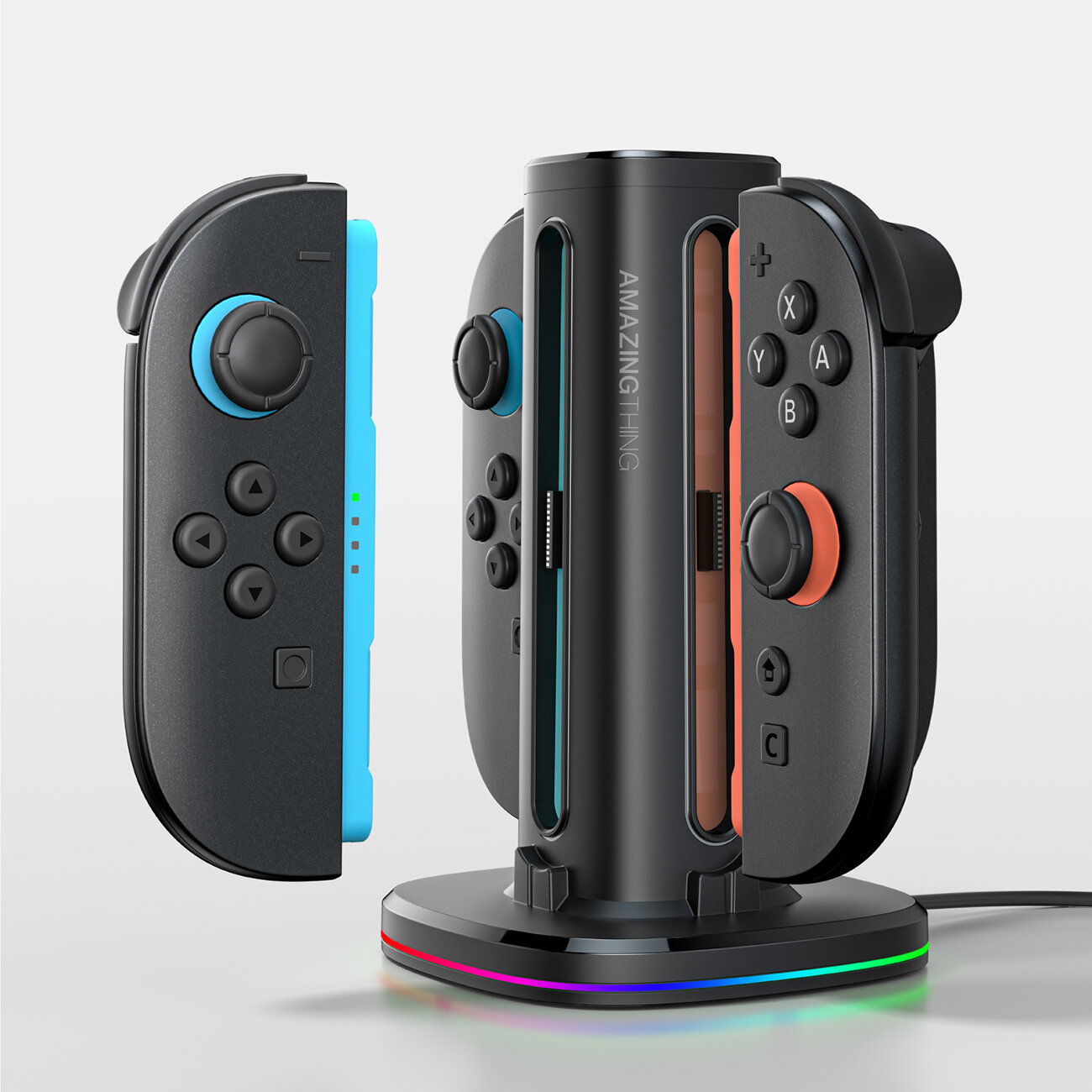 Czarna stacja ładująca z logo \'AMAZINGTHING\' przeznaczona do kontrolerów Nintendo Switch. Obok stacji znajdują się dwa kontrolery w kolorach niebieskim i czerwonym.