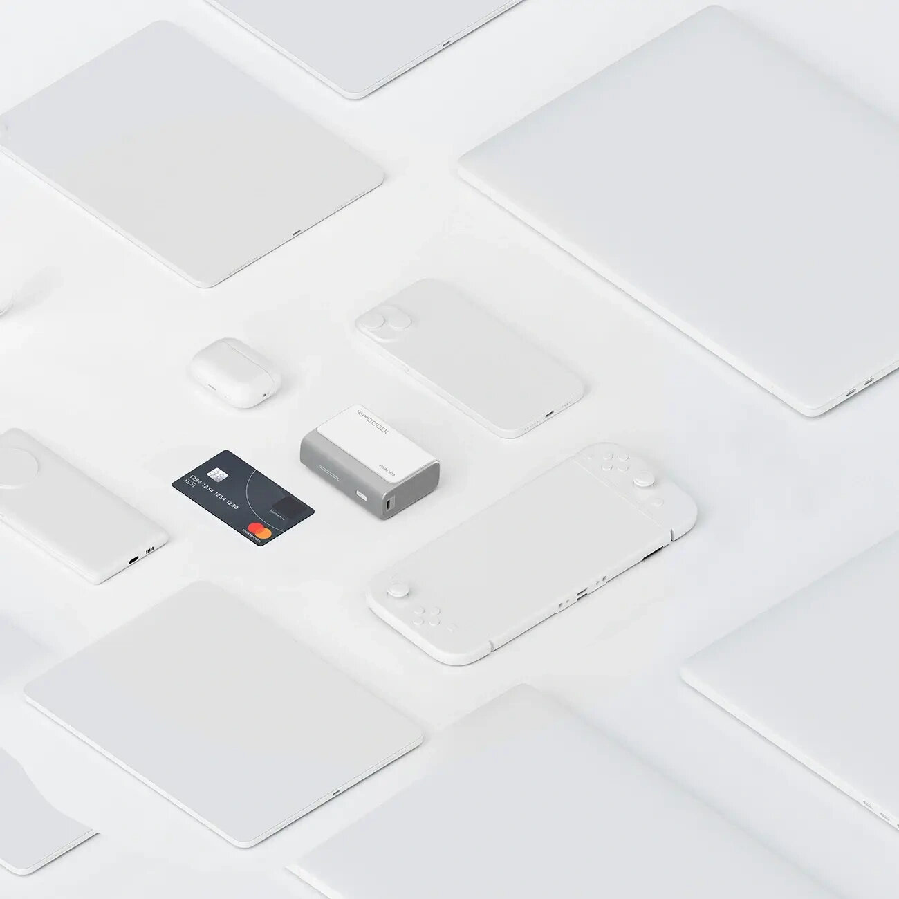 Na obrazie widoczny jest szary power bank z napisem \'Cuktech\' otoczony różnymi urządzeniami elektronicznymi, w tym kartą płatniczą. Wszystkie przedmioty są ułożone na jasnym tle.