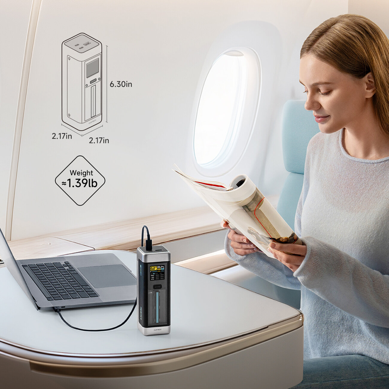 Na zdjęciu widać osobę siedzącą w samolocie, trzymającą czasopismo, obok której na stoliku znajduje się laptop podłączony do powerbanku. Obok powerbanku widoczny jest schemat z wymiarami: 6.30in x 2.17in x 2.17in oraz informacja o wadze: ≈1.39lb.