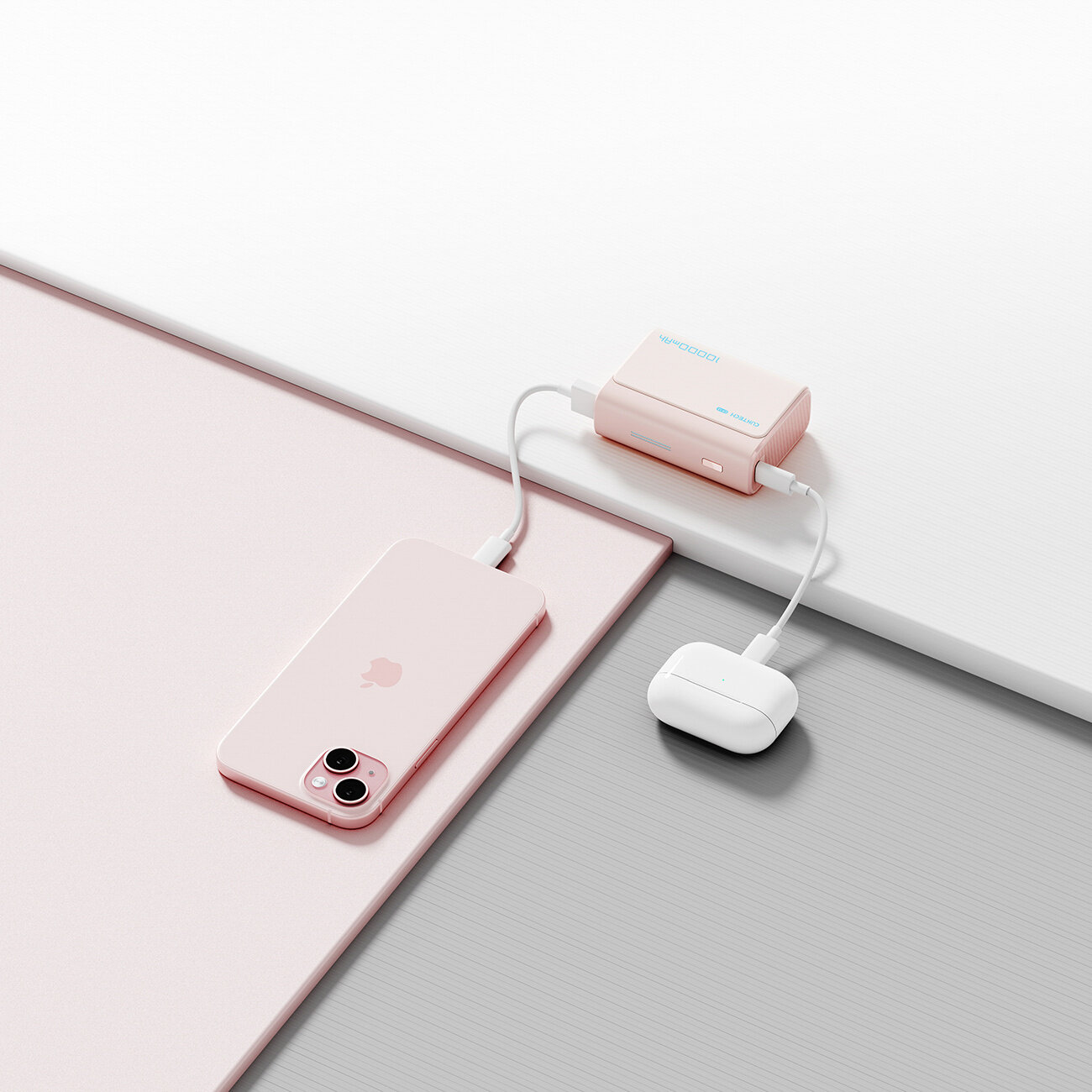 Na obrazie widoczny jest różowy powerbank podłączony do różowego smartfona i białych słuchawek bezprzewodowych. Na powerbanku znajduje się logo \'Cuktech\'.
