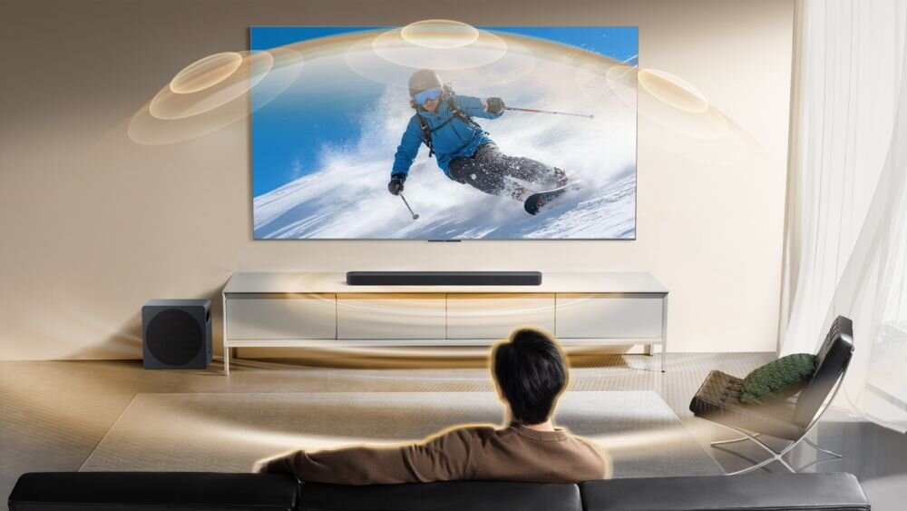 Soundbar TCL A65K przetwornik kopułkowy odbicie dźwięku od sufitu efekt wysokości, Soundbar pod telewizorem z narciarzem na ekranie, emitujący łukowe fale dźwiękowe w stronę siedzącego mężczyzny