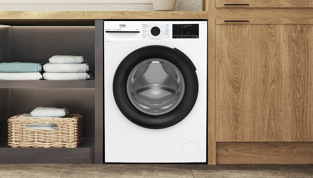 PRALKA BEKO B300 XBM3WFU49415W Pralka Beko z załadunkiem od frontu została zabudowana pod blatem w pralni lub pomieszczeniu gospodarczym. Obok urządzenia znajdują się półki z ręcznikami i koszem na pranie, a drewniana zabudowa oraz duże okno podkreślają estetyczny charakter wnętrza