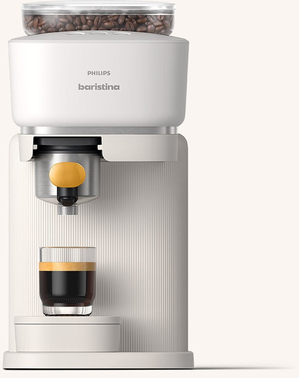 Na obrazie widoczny jest ekspres do kawy z logo \'PHILIPS baristina\'. Pod dyszą znajduje się szklanka z kawą, a na górze ekspresu widać pojemnik z ziarnami kawy.