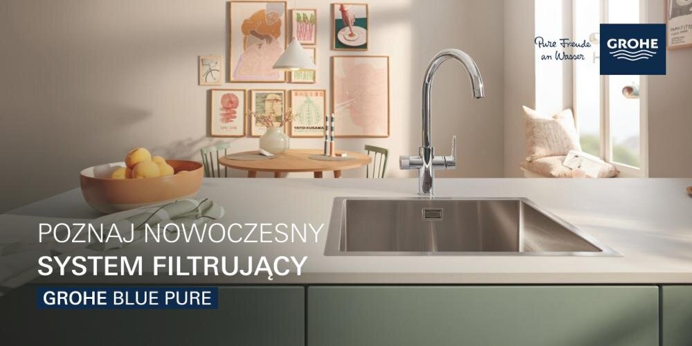 Kuchnia z nowoczesnym zlewem i chromowaną baterią GROHE. Na ścianie widoczne są obrazy, a na blacie stoi misa z owocami i kubek.