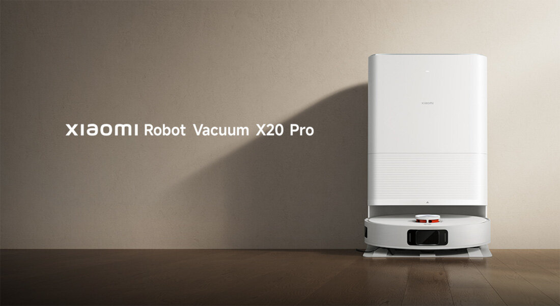 Na obrazie widoczny jest biały robot sprzątający z napisem \'XIAOMI Robot Vacuum X20 Pro\' na ścianie obok. Robot stoi na drewnianej podłodze przy ścianie.