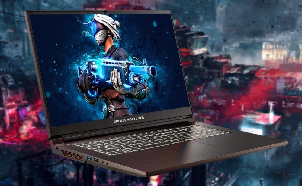 Laptop z logo \'DREAM MACHINES\' na dolnej ramce ekranu, wyświetlający grafikę postaci w futurystycznym stroju z bronią. W tle widoczny jest rozmyty, kolorowy krajobraz miejski.