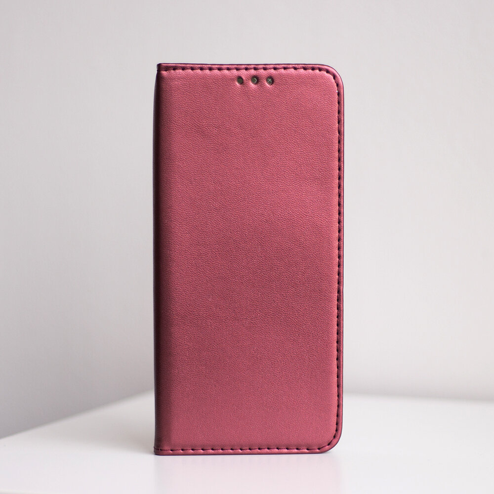 Burgundowe etui na telefon z trzema otworami na górze, stojące na białej powierzchni. Etui ma gładką teksturę i zaokrąglone krawędzie.