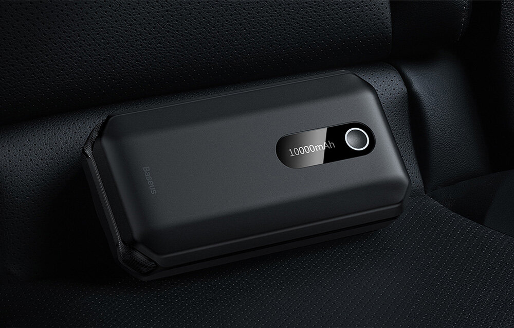 Czarny powerbank z napisem \'10000mAh\' leży na ciemnym, teksturowanym materiale. Na obudowie widoczne jest logo \'Baseus\'.