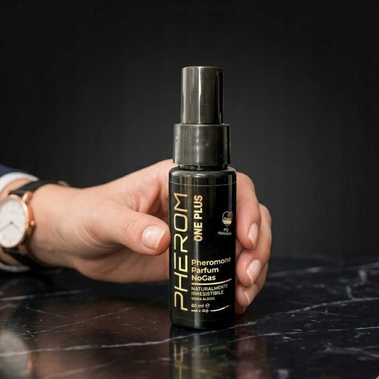 Osoba trzyma czarną butelkę perfum z napisem \'PHEROM ONE PLUS Phéromone Parfum NoGas NATURALMENT IRRESISTIBLE 60 ml e\'.