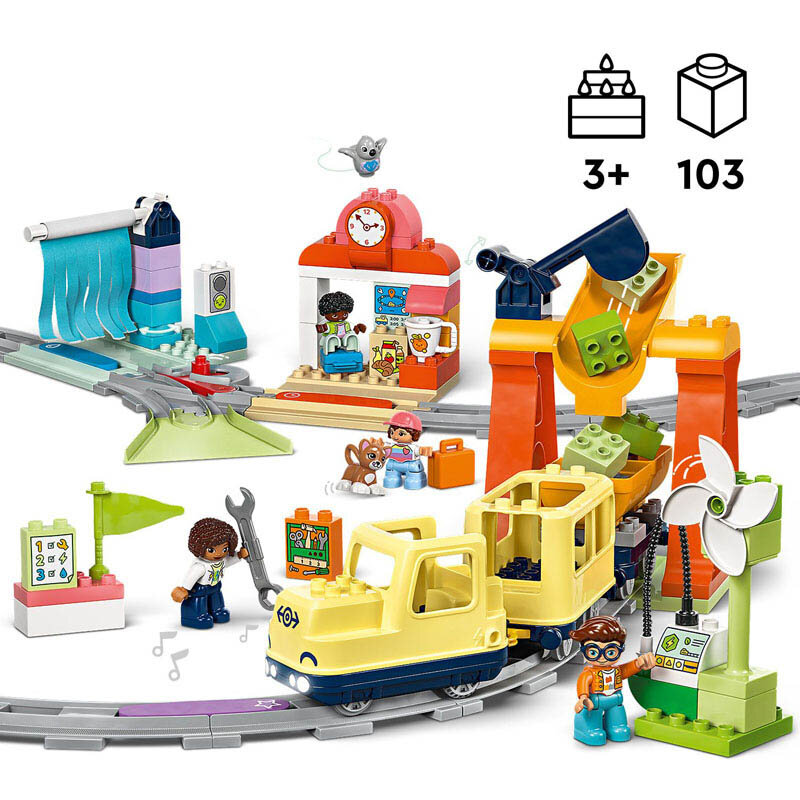 Zestaw LEGO DUPLO przedstawia duży interaktywny pociąg miejski z torami, stacją i różnymi akcesoriami. Na obrazie widoczne są także figurki postaci oraz elementy takie jak zegar, flaga i kwiat.