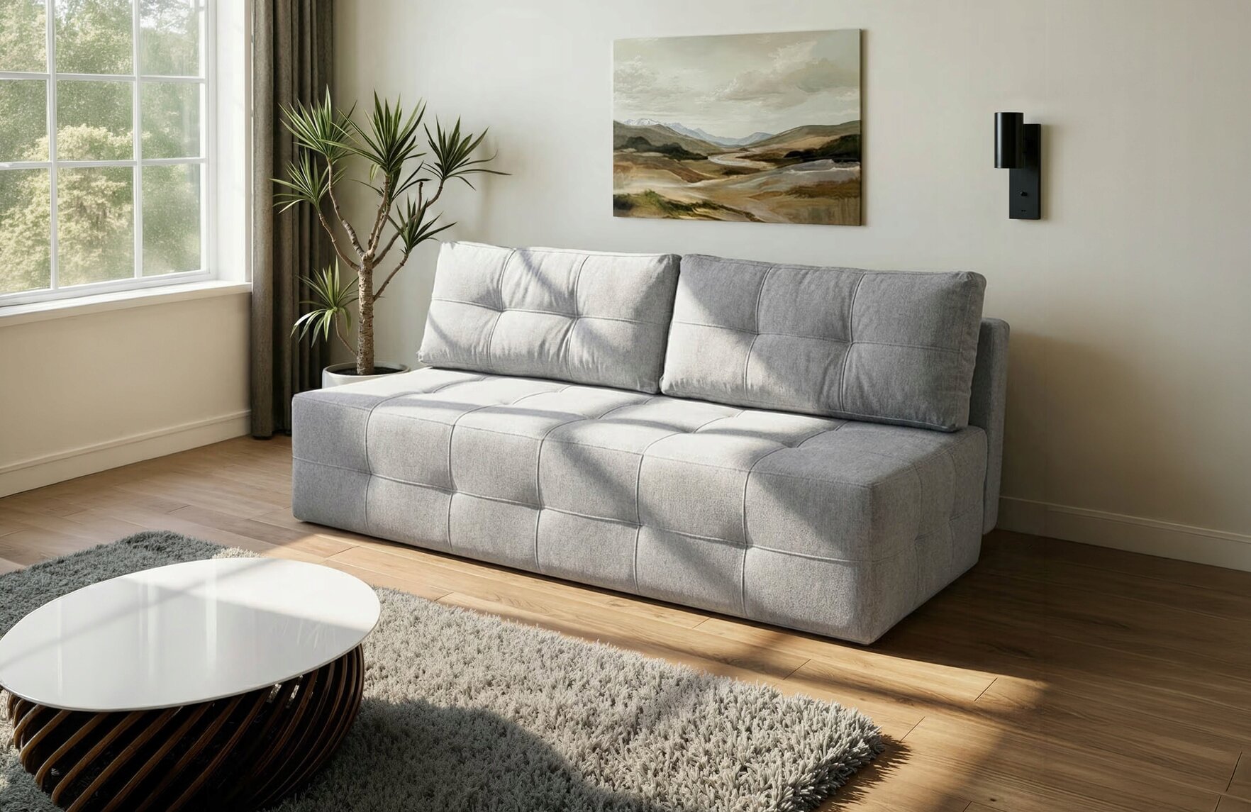 Na obrazie znajduje się szara sofa z funkcją spania, ustawiona w salonie z drewnianą podłogą. Obok sofy stoi roślina doniczkowa, a na ścianie wisi obraz przedstawiający krajobraz.