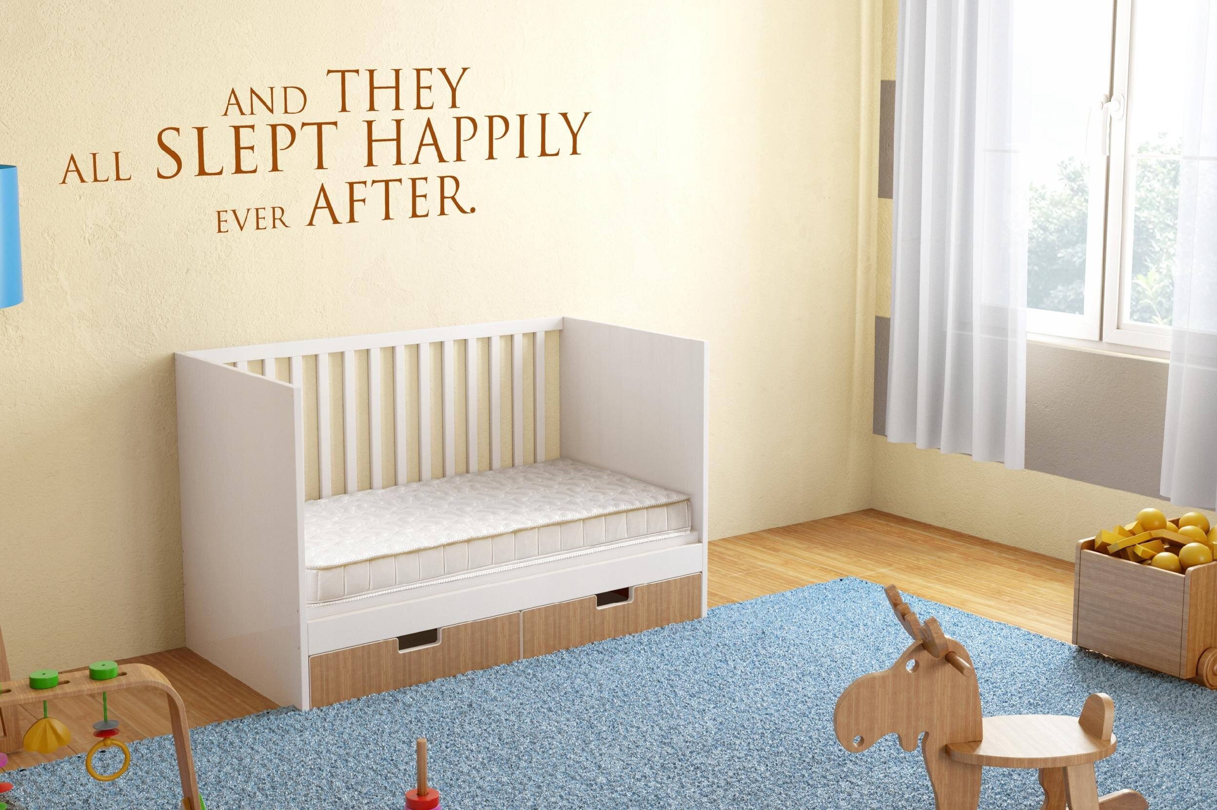 Pokój dziecięcy z łóżeczkiem, w którym znajduje się materac. Na ścianie widnieje napis: \'AND THEY ALL SLEPT HAPPILY EVER AFTER.\'