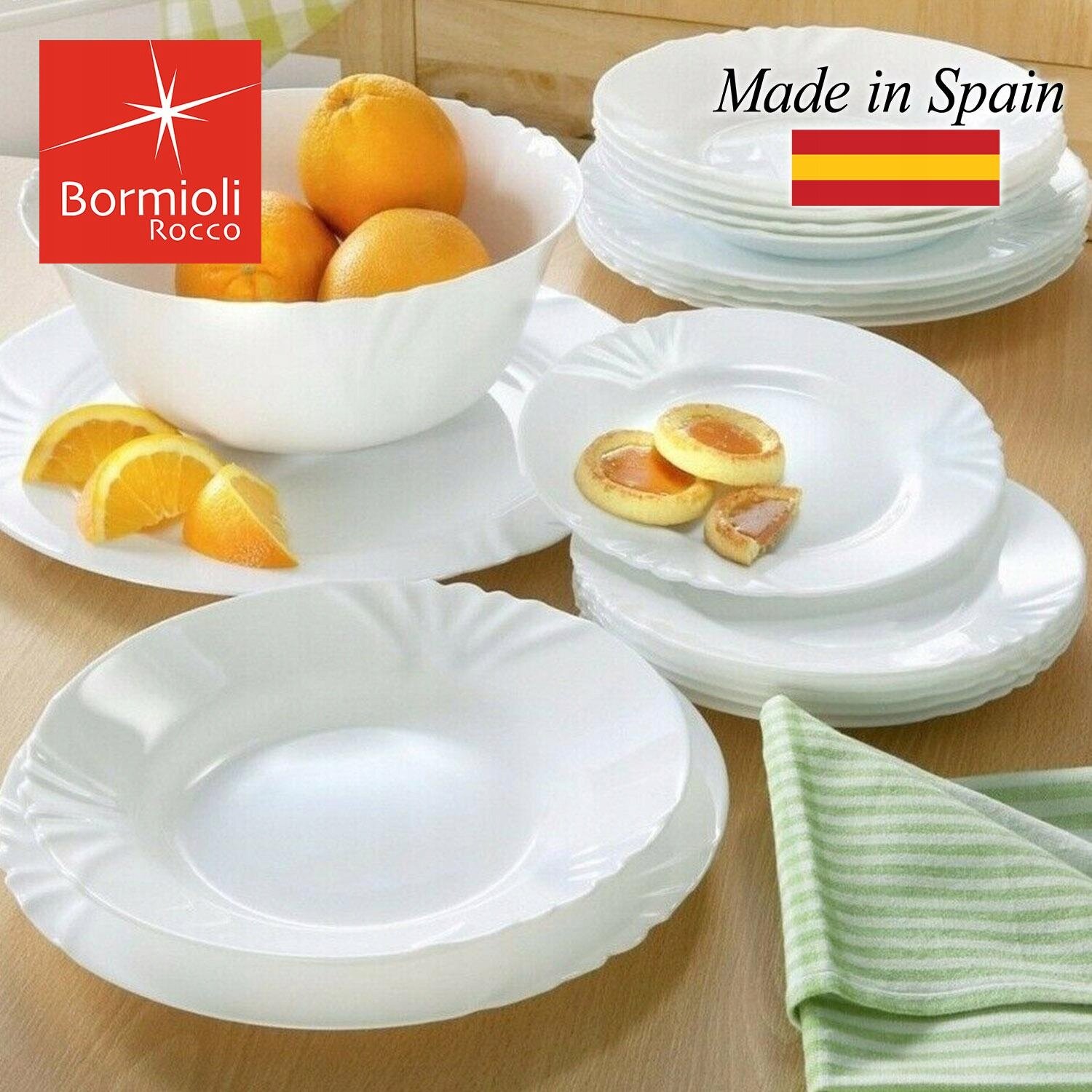 Na obrazie widoczny jest zestaw białych, głębokich talerzy oraz miska z pomarańczami. W lewym górnym rogu znajduje się logo \'Bormioli Rocco\', a obok napis \'Made in Spain\' z flagą Hiszpanii.